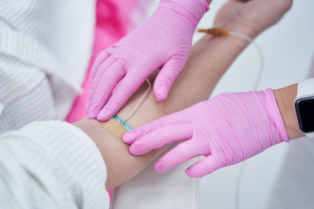Close Up Of A Care Provider's Hands Putting IV In Arm